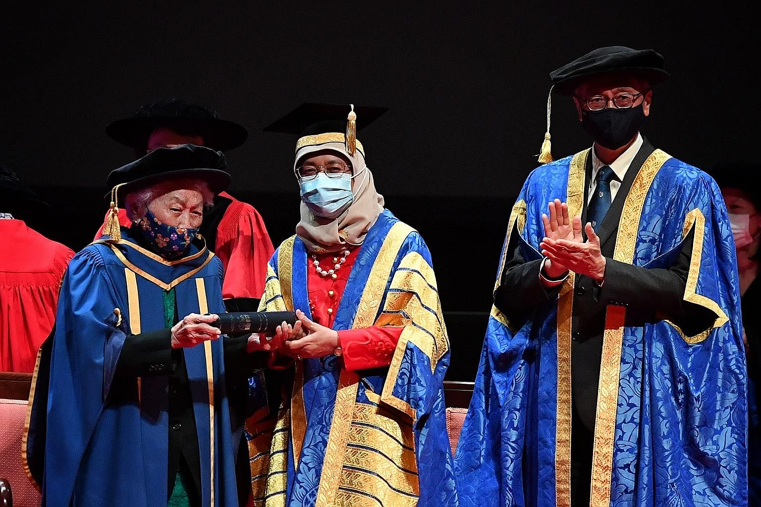 Dr Oon Chiew Seng, 104, receiving an honorary National University of Singapore (NUS) degree from President Halimah Yacob, who is also NUS chancellor, at a ceremony held at the University Cultural Centre yesterday. Dr Oon was one of Singapore's first 