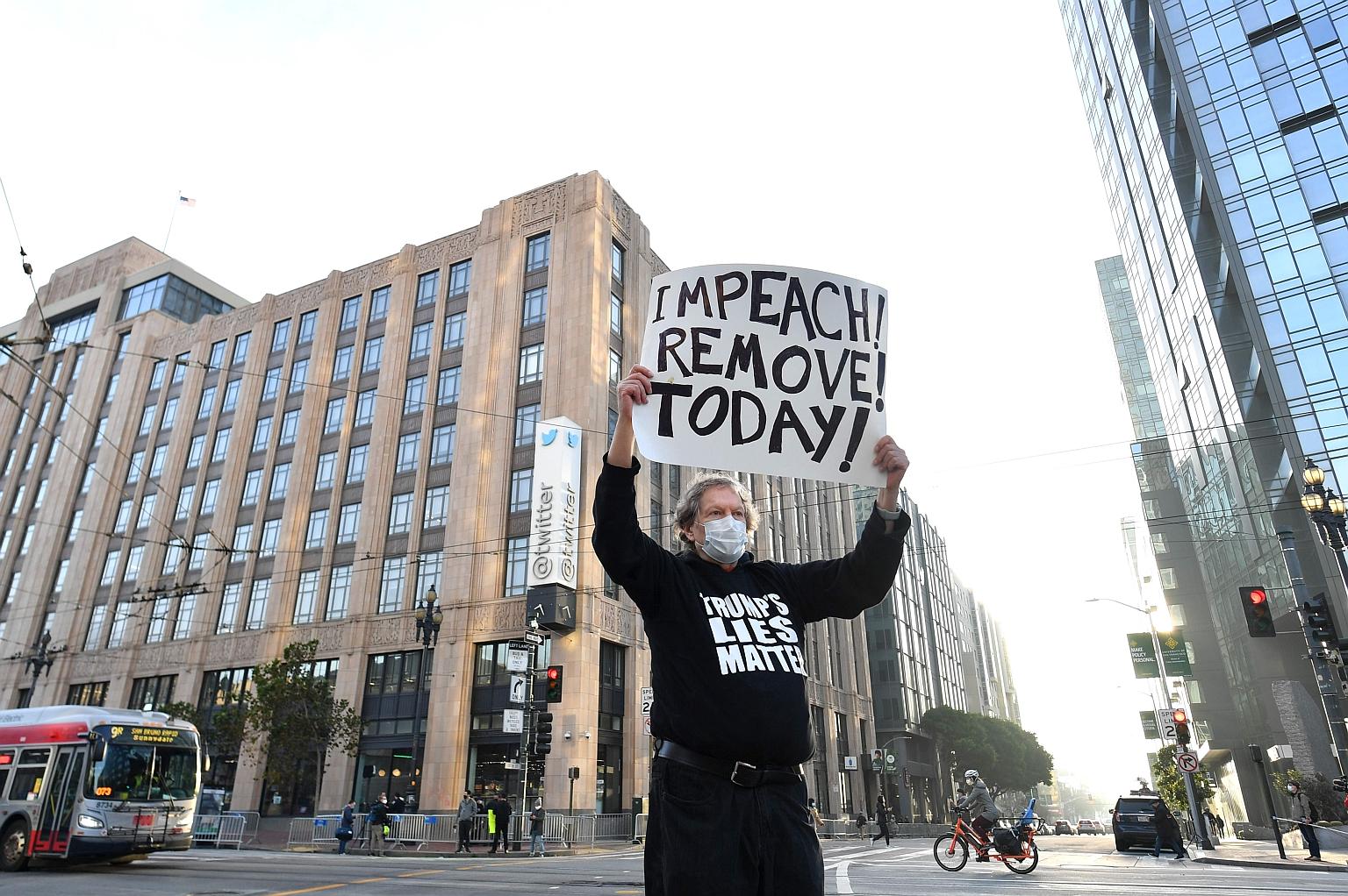 Protester Kenneth Lundgreen holding up a sign calling for President Donald Trump's impeachment as police set up barricades outside Twitter's headquarters in San Francisco, California, on Monday. Twitter suspended Mr Trump's account after thousands of