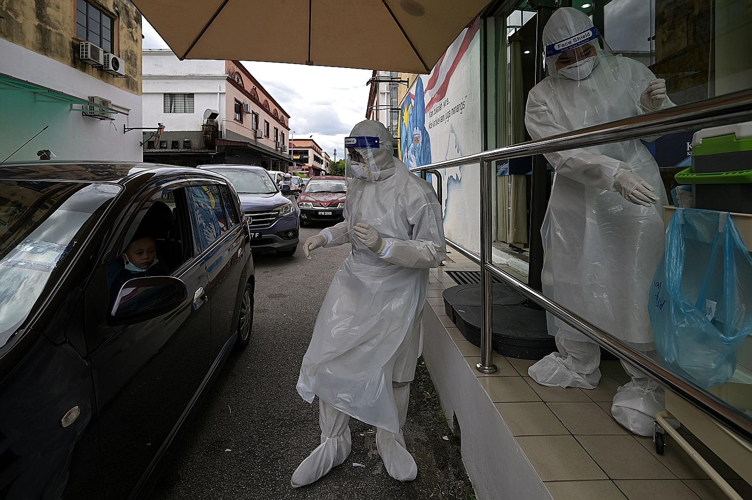 Medical personnel conducting Covid-19 testing at a drive-through centre outside Ajwa Private Clinic in Shah Alam on the outskirts of Kuala Lumpur yesterday. Malaysia's declaration of a state of emergency to deal with the worsening pandemic could rais