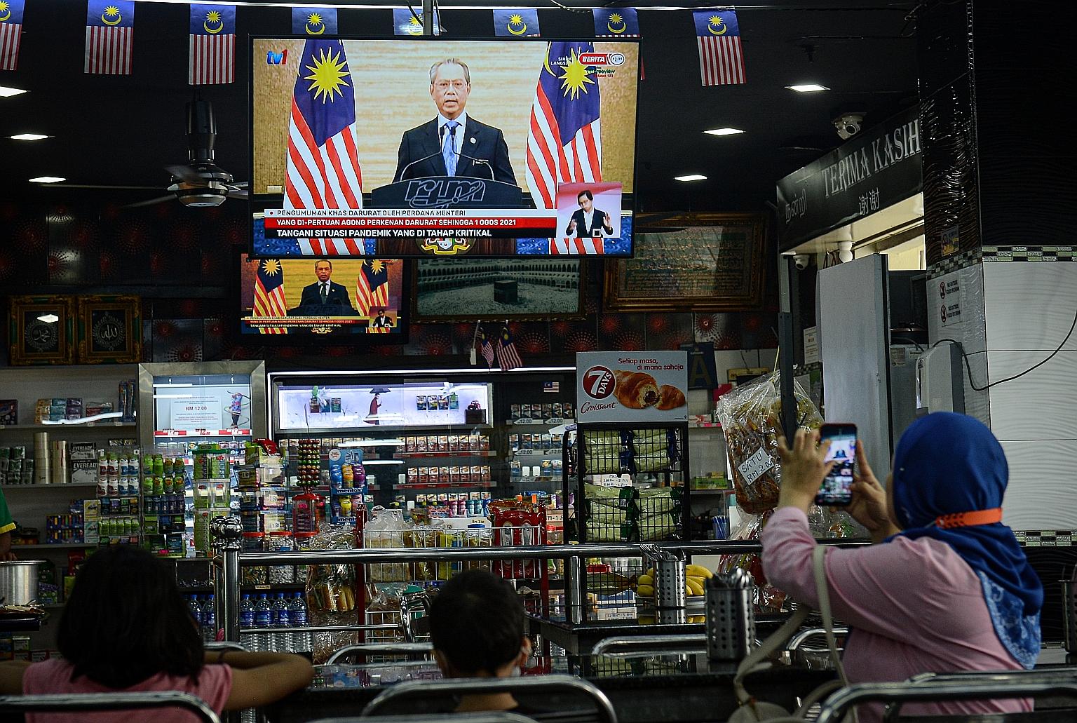 Kuala Lumpur residents watching yesterday's live national address by Prime Minister Muhyiddin Yassin where he announced the state of emergency and sought to instil calm, saying that the government and public services would continue to function normal