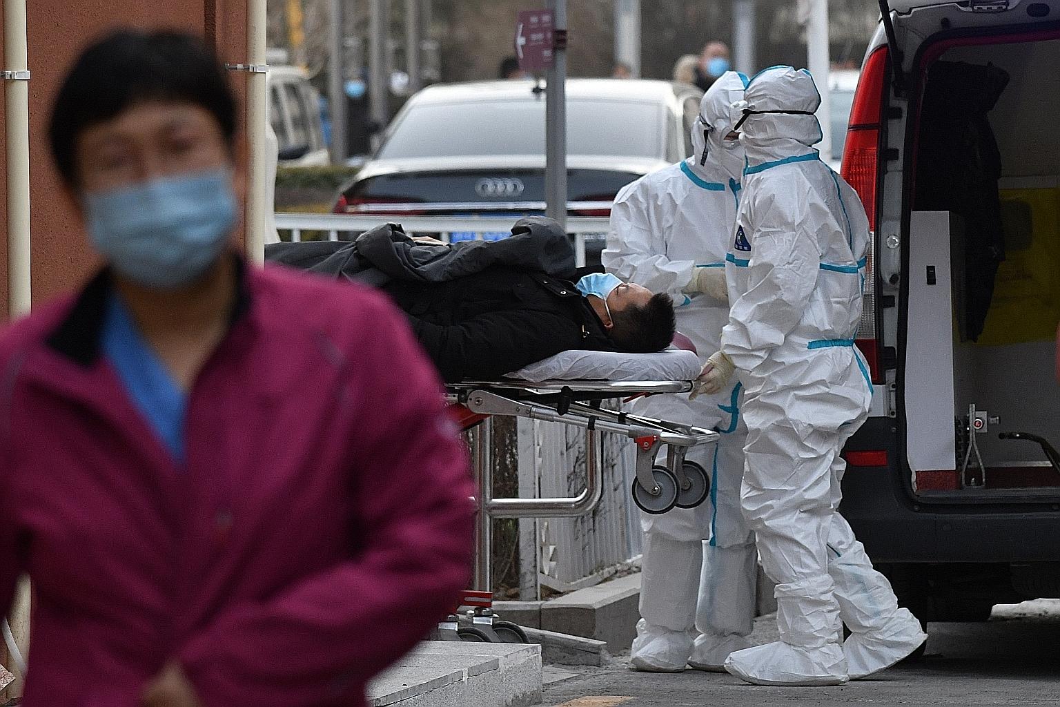 Medical workers wearing protective suits moving a patient to the fever clinic at a hospital in Beijing yesterday. Most of the new patients were reported near the capital city, but a province in north-east China also saw a rise in new cases. There wer
