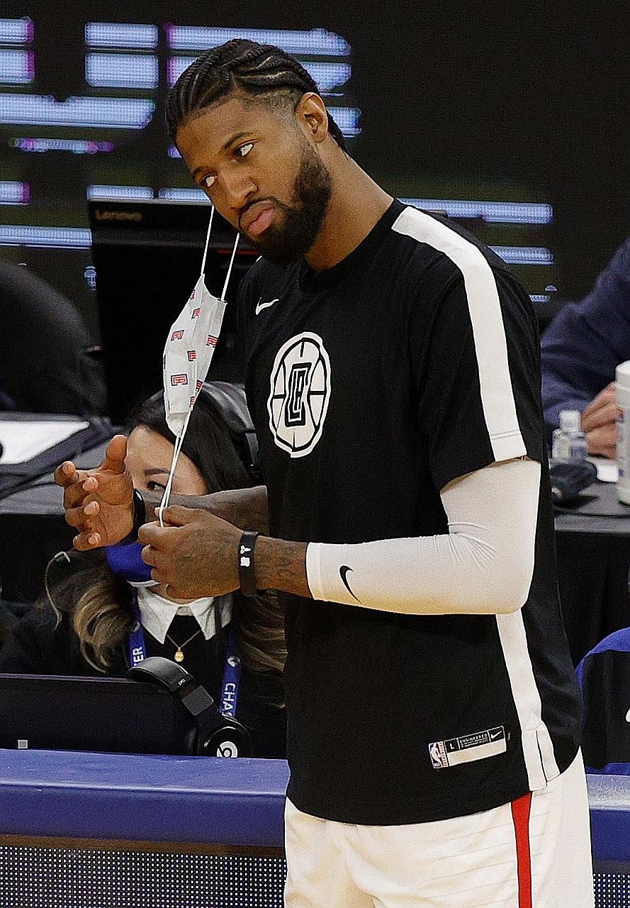 Clippers guard Paul George taking off his mask before checking back into the game against the Warriors at Chase Centre. NBA players must wear masks on the bench at all times.