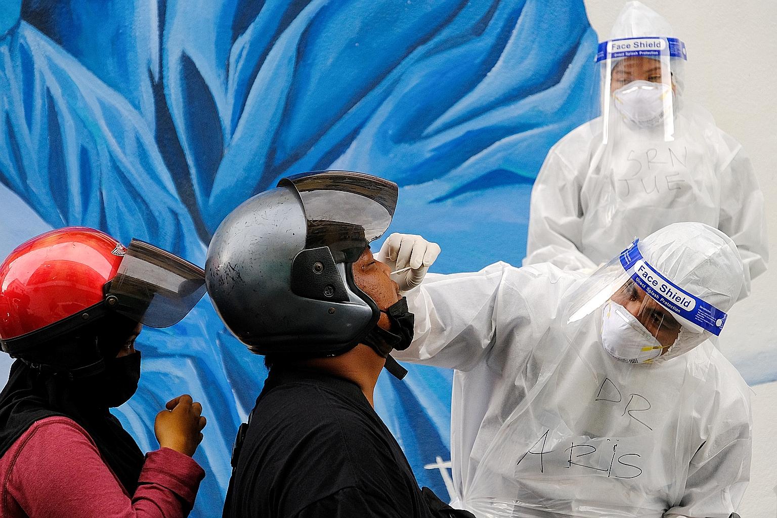 A motorist in Selangor getting swabbed at a drive-through Covid-19 testing centre. A two-week movement control order began yesterday in five Malaysian states and all three federal territories. PHOTO: BLOOMBERG