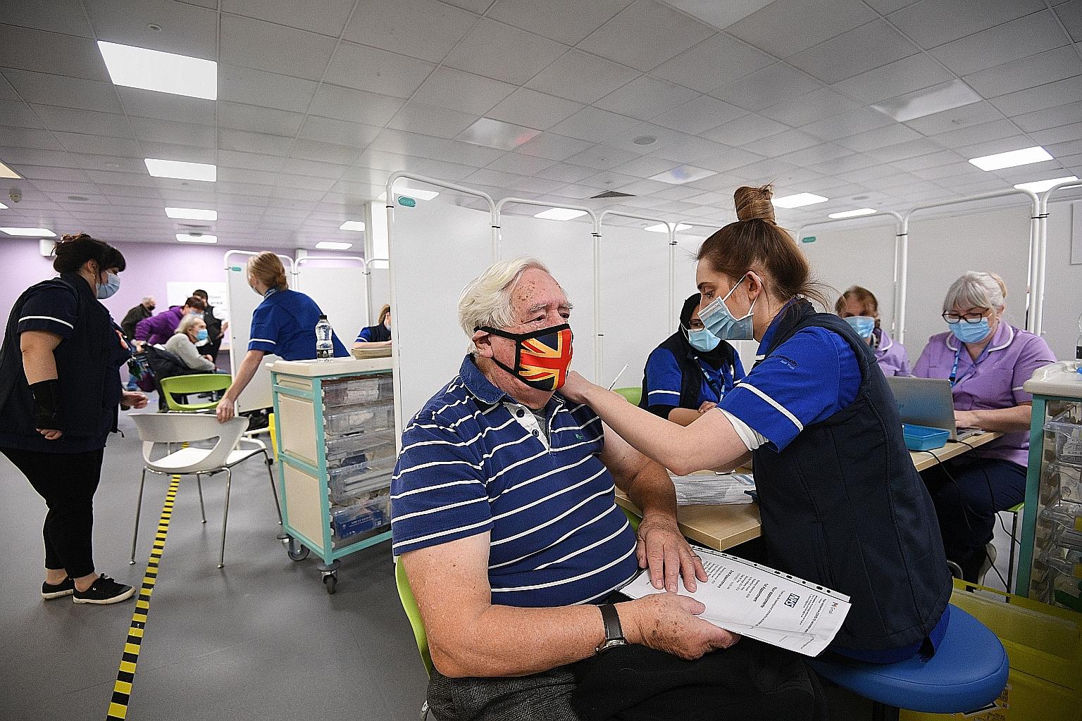 A man receiving a Covid-19 vaccine in Britain on Monday. With the vaccine roll-out gathering steam, some of the funds have been rotating to medium-term winners, recovery plays and growth stocks. PHOTO: BLOOMBERG