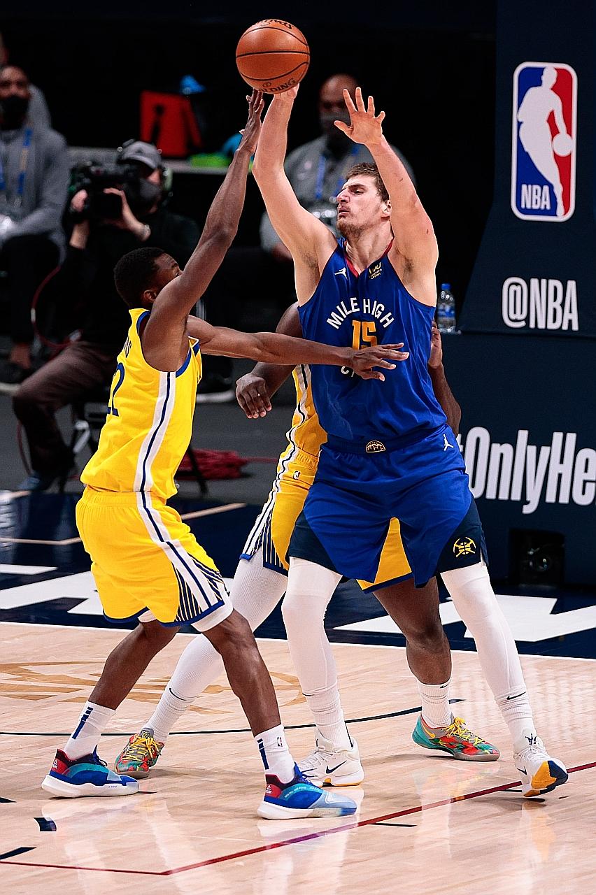 Denver Nuggets centre Nikola Jokic passes the ball over Golden State Warriors' Andrew Wiggins during their home win on Thursday. The Serb is averaging a triple-double on 24.3 points (17th), 10.9 rebounds (8th) and leading the NBA in assists (10.5).