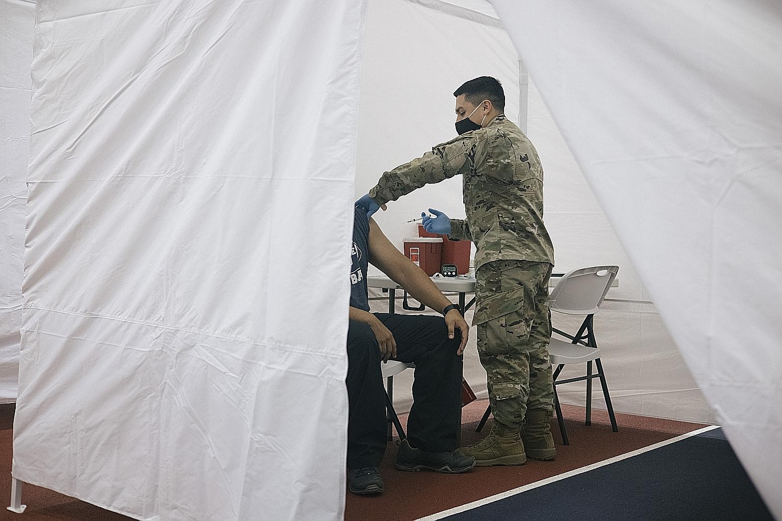Mr Emmanuel Alfaro, a senior airman and medic with the 175th Air National Guard, administering a Covid-19 vaccine shot in Maryland this week. With the coronavirus pandemic raging in the US and a vaccine programme to control it struggling, governors a