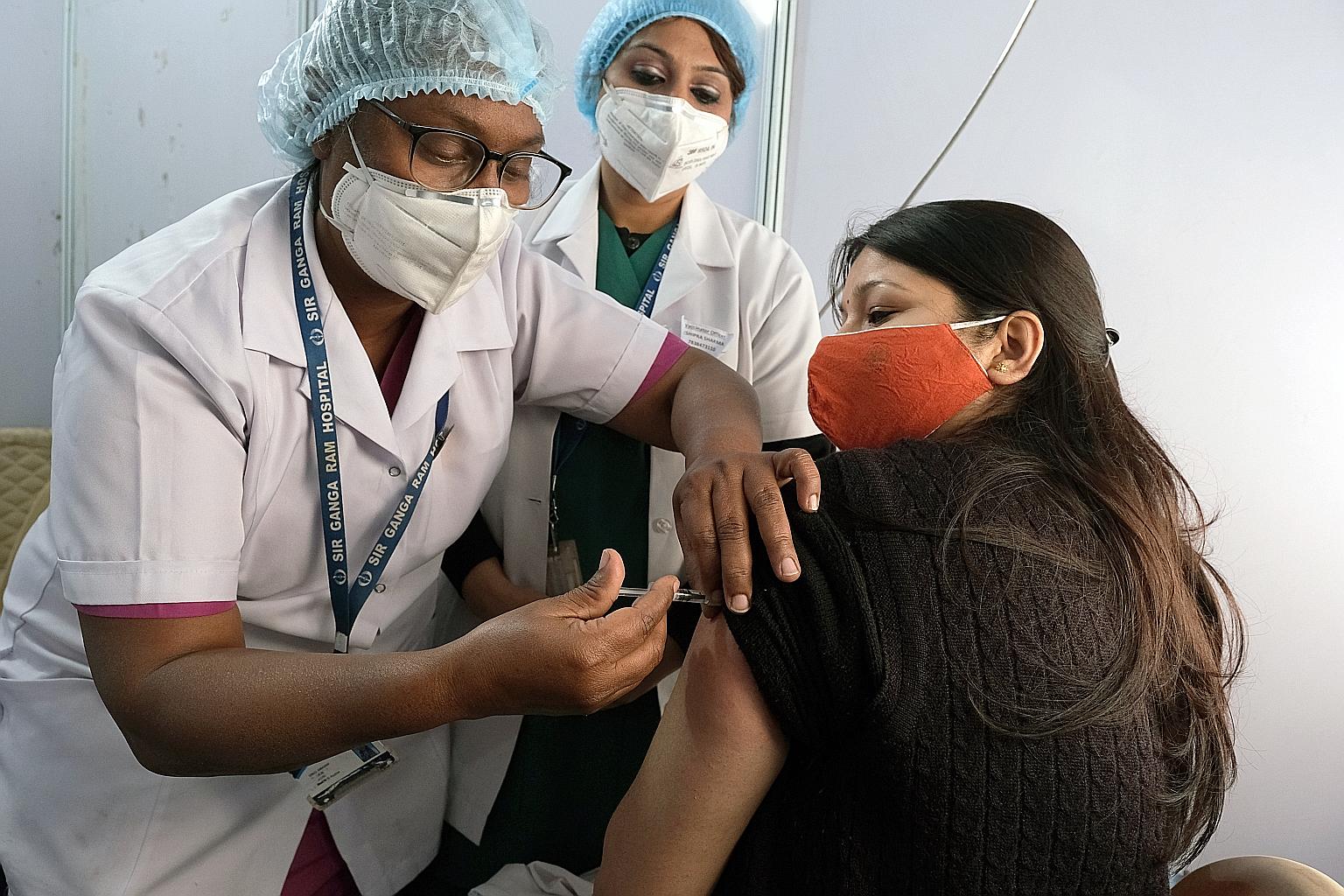 A woman receiving Oxford-AstraZeneca's Covishield vaccine at the Ganga Ram Hospital in New Delhi on Saturday. The authorities have given emergency-use approval for Covishield and the home-grown Covaxin, which has yet to complete its phase three trial