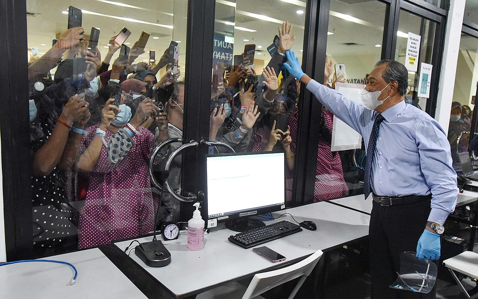 Prime Minister Muhyiddin Yassin waving to Covid-19 patients at a quarantine facility in Serdang, outside Kuala Lumpur, on Tuesday. Malaysia registered 4,008 new cases yesterday, a week after new curbs kicked in. PHOTO: AGENCE FRANCE-PRESSE