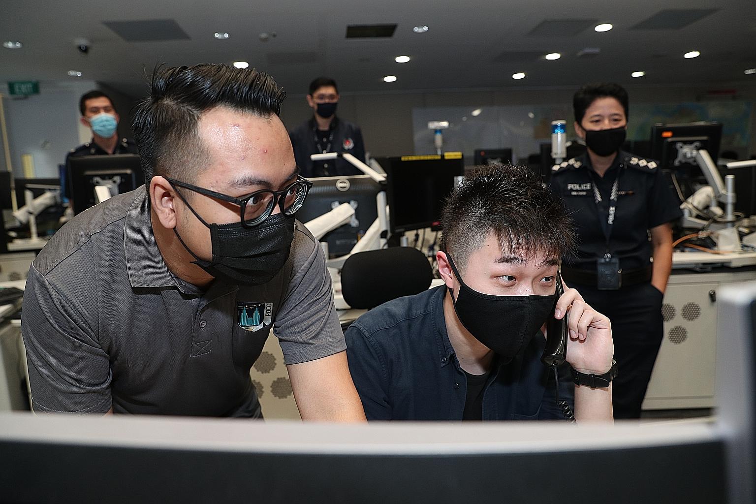 Straits Times reporter David Sun answering a simulated 999 call as emergency communications officer Mohamad Suhaimi Ami (left) looks on.