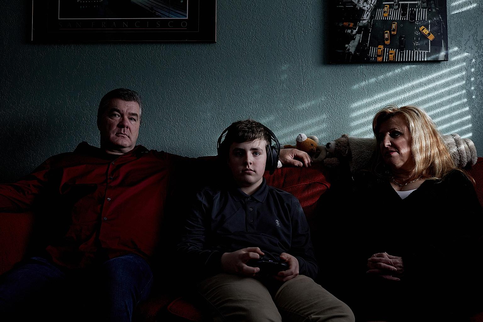 Mr John Reichert with his teenage son, James, and his wife, Kathleen. James spends about 40 hours a week on Xbox and his mobile phone, to his father's chagrin.
