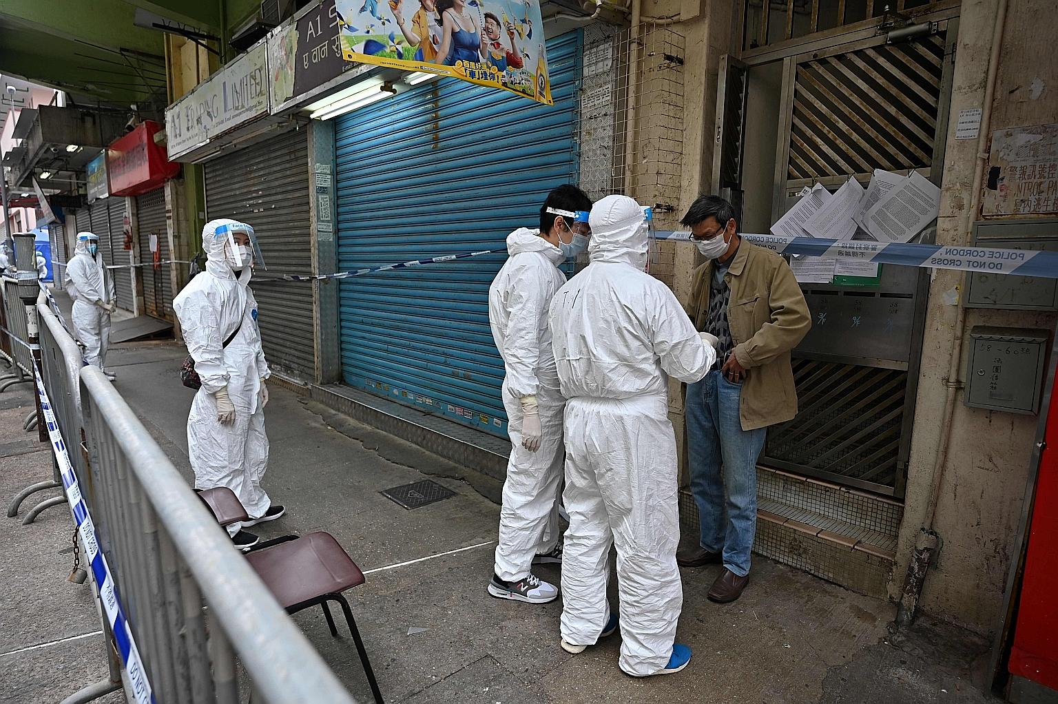 Hong Kong health workers speaking yesterday to a resident of Jordan, a densely populated neighbourhood in Kowloon peninsula which was locked down on Saturday. Home Affairs Secretary Caspar Tsui said people declared Covid-19 negative were allowed from