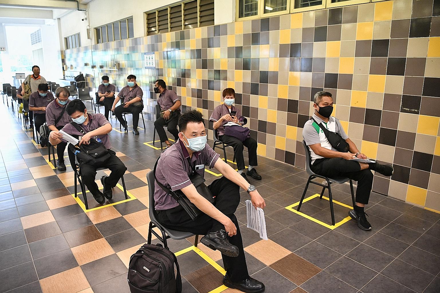 Employees of bus and train operators waiting to receive their first dose of the Covid-19 vaccine at a vaccination centre at the former Hong Kah Secondary School yesterday. They were among the first batch of 12,000 land transport workers to be offered