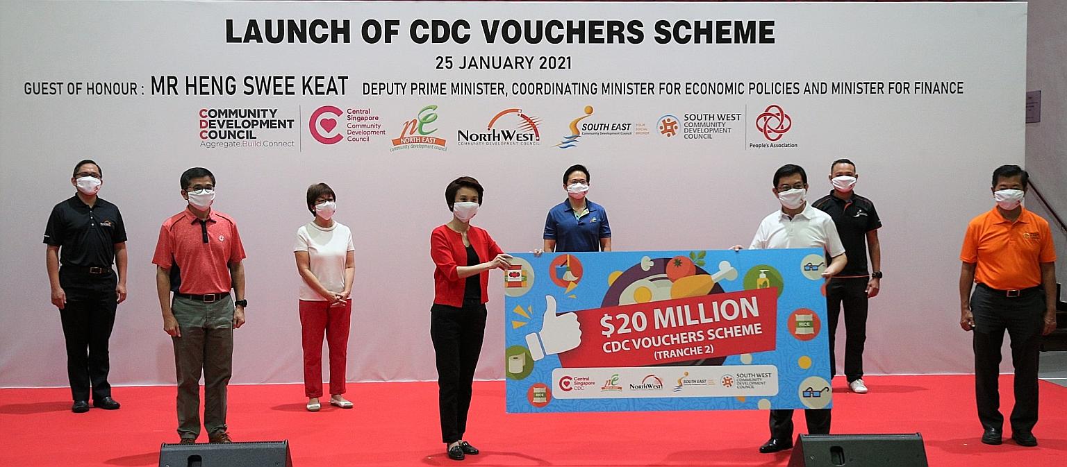 Deputy Prime Minister Heng Swee Keat and South West District Mayor Low Yen Ling holding a placard at the launch of the second tranche of vouchers under the Community Development Council Vouchers Scheme at Bedok Community Centre yesterday. With them a