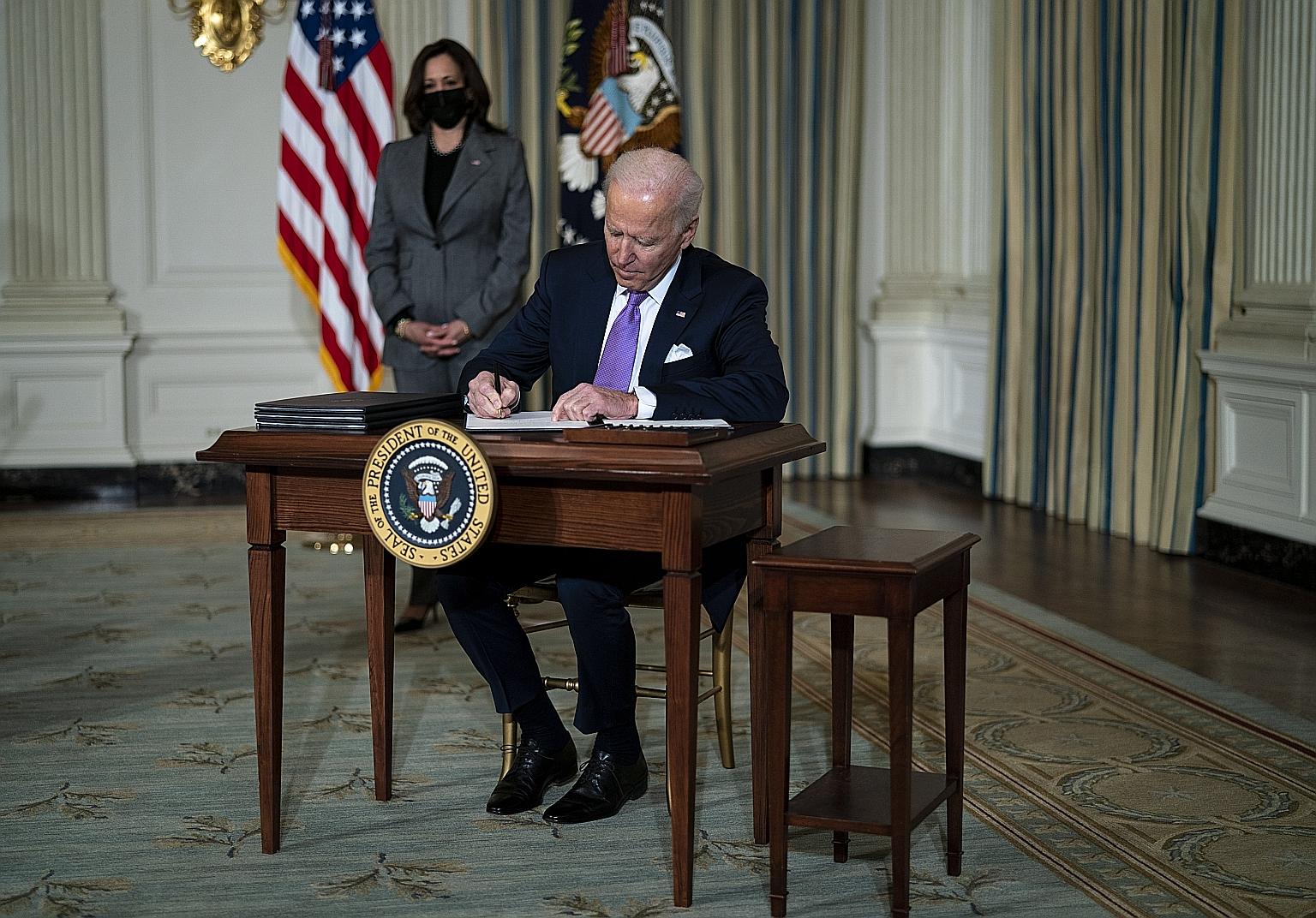 United States President Joe Biden signing executive orders, with Vice-President Kamala Harris looking on, in the State Dining Room of the White House on Tuesday. Mr Biden said that in the coming weeks he would reaffirm a federal "commitment to divers