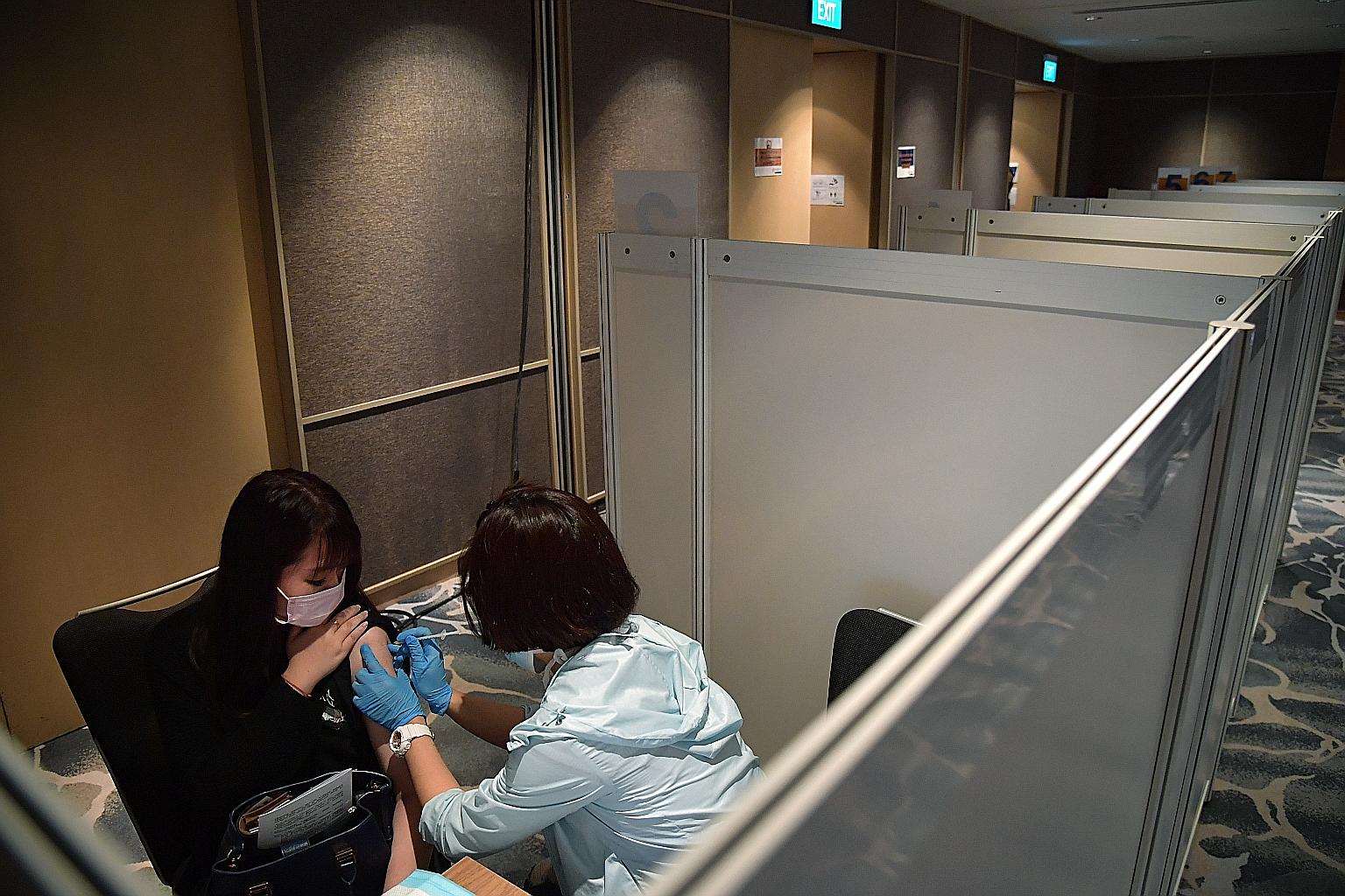 Below: A hotel employee getting her Covid-19 vaccination jab last Thursday. Experts say that with the recent re-emergence of community cases, albeit still in relatively low numbers, a successful vaccination programme is likely to significantly preven