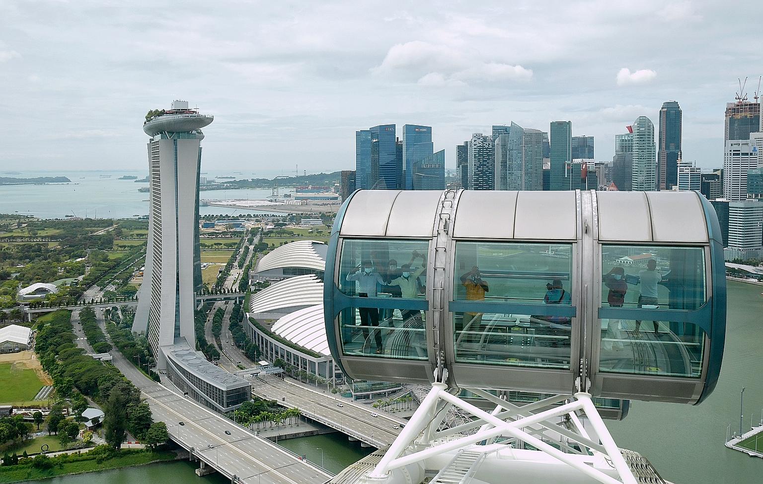 Migrant workers waving from the capsules on the Singapore Flyer yesterday, when 620 of them visited the landmark observation wheel under an initiative by ItsRainingRaincoats, Klook and Singapore Flyer, with tickets donated by the public and an instit