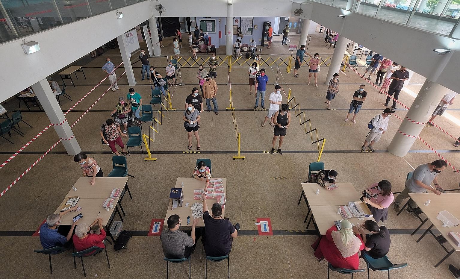 Residents collecting their TraceTogether tokens at Kampong Kembangan Community Club last December. So far, more than 80 per cent of the population have either downloaded the TraceTogether app or collected the token. ST PHOTO: GAVIN FOO