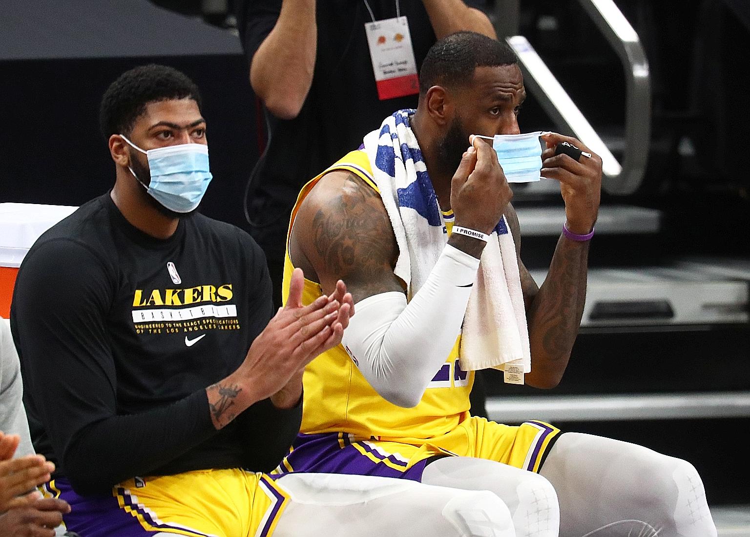 Lakers star LeBron James putting on a mask after sitting on the bench next to Anthony Davis during a pre-season NBA game in December.