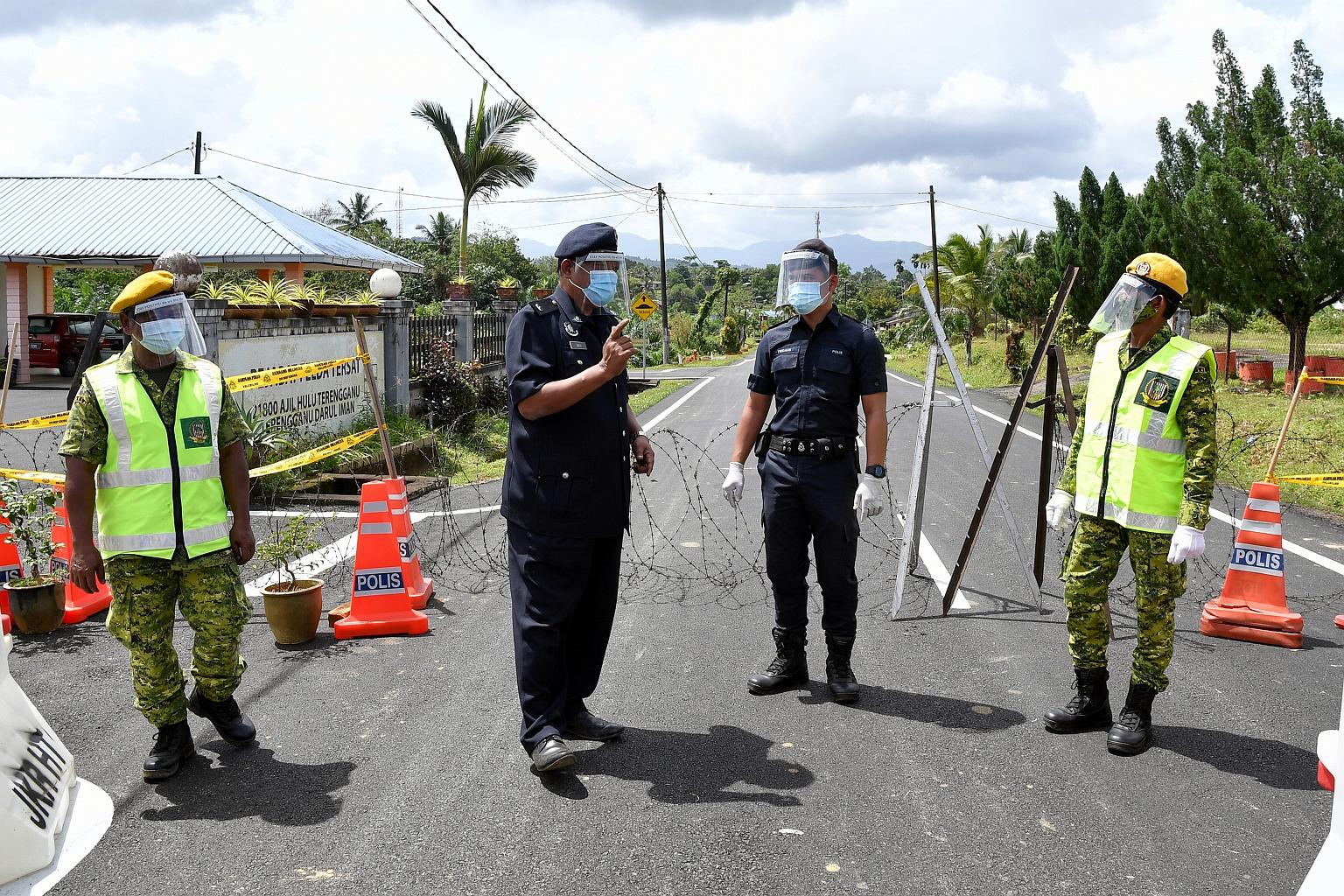 A roadblock at the entrance of the Felda Tersat settlement in Hulu Terengganu district, Terengganu, that is manned by police officers and members of the people's volunteer corps. The army, which has been helping the police man roadblocks in Malaysia'