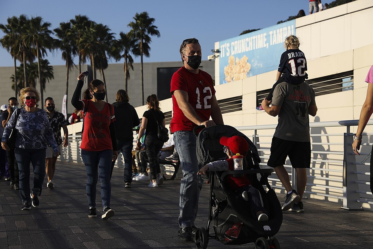 People wearing protective face masks walking along the Tampa Riverwalk last Sunday. Fans will be given KN95 masks when entering the stadium for the Super Bowl tomorrow.