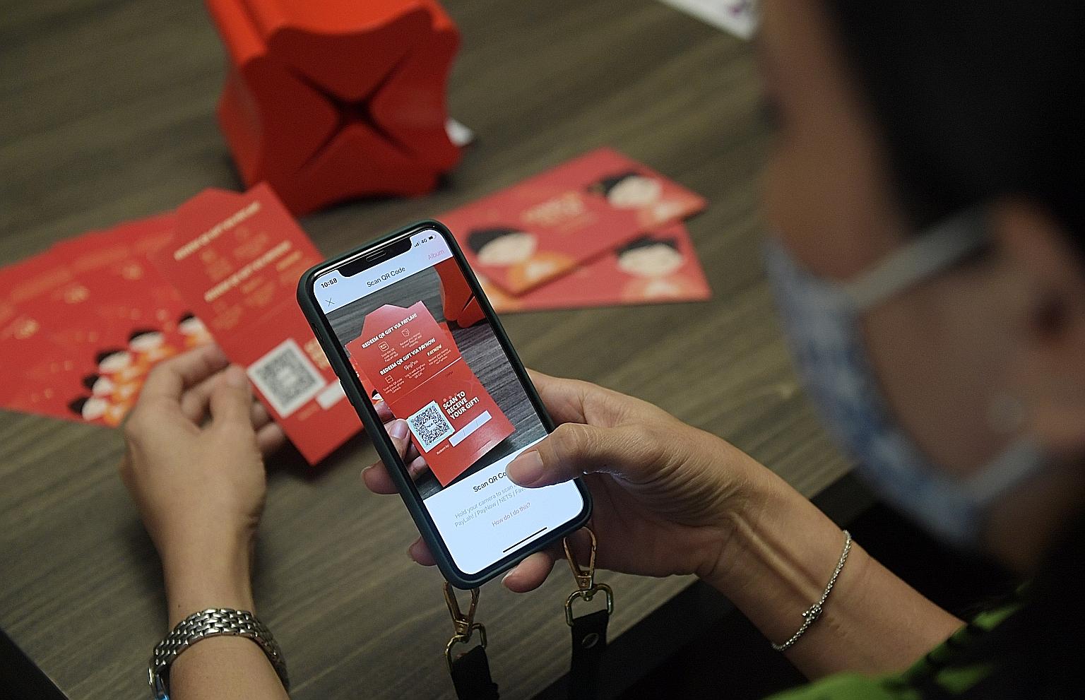 A customer scanning a QR code to receive a DBS Bank QR Gift card, a substitute for the traditional red packet. Some 32,000 DBS QR Gift cards were loaded with a total of $2 million as at last Saturday, up from 18,000 QR Gift cards with about $660,000