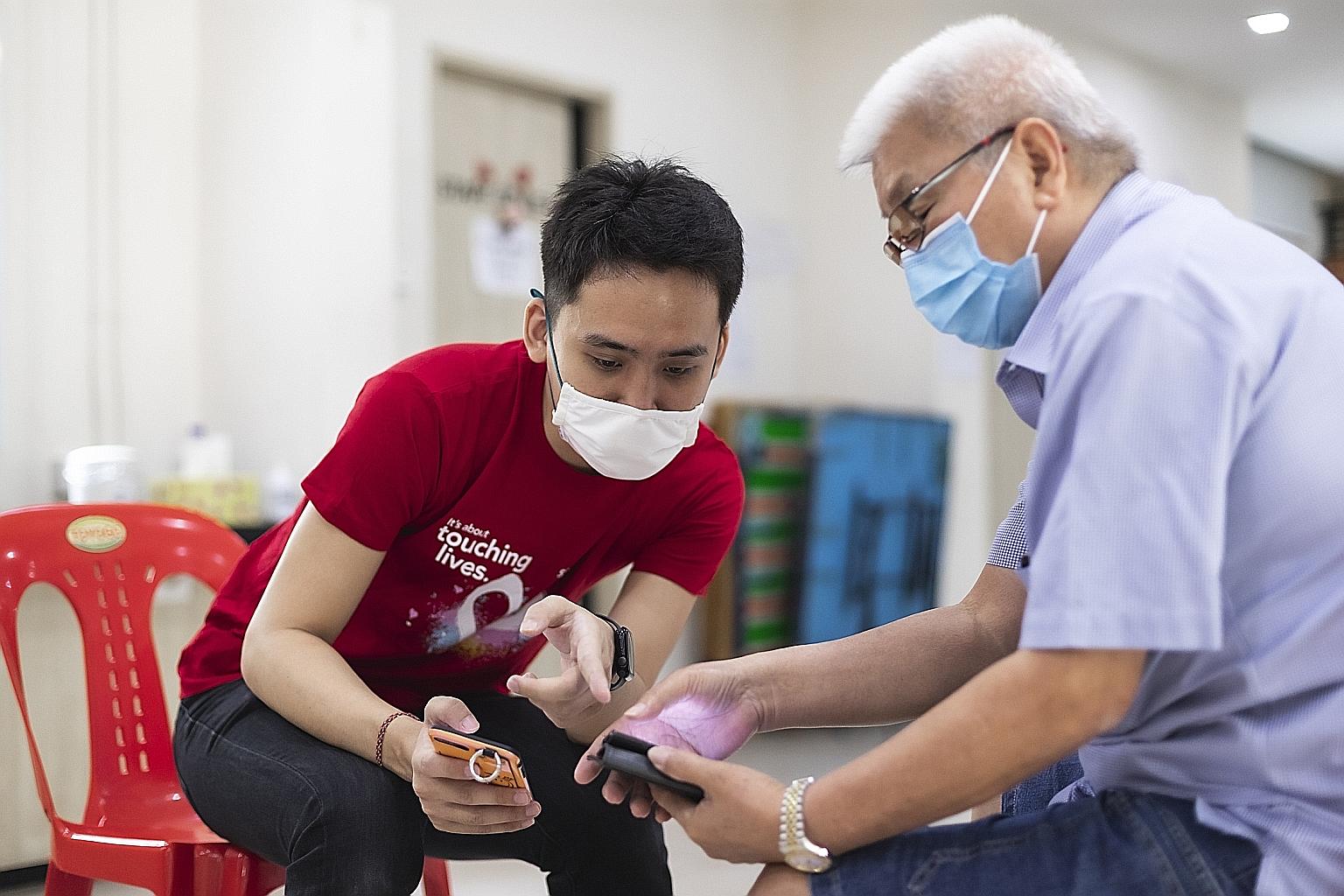 Singtel volunteer Quek Zikang (left) guiding Mr Tan Kie Hwa at the first Digital Silvers session, held at a Thye Hua Kwan Seniors Activity Centre in Ang Mo Kio last September. The programme aims to help seniors learn how to use digital devices and go