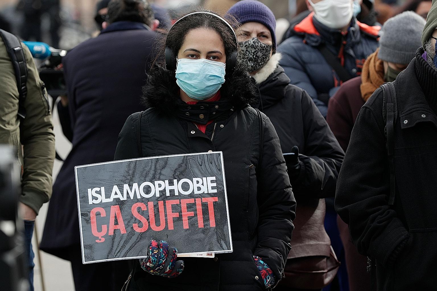 A woman holding a placard that reads "Enough of Islamophobia" during a protest against the Bill in Paris on Sunday. The legislation aims to tighten rules on issues like religious-based education.