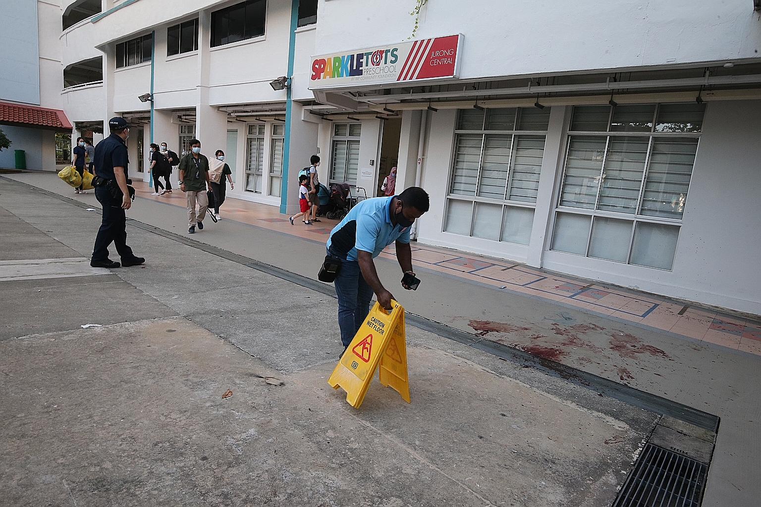 Police and workers at the scene where Ms Tham Mee Yoke was found lying motionless with multiple stab wounds on Tuesday. Zheng Xianfeng was charged yesterday with her murder.