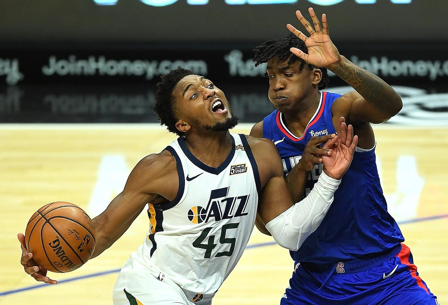 Jazz guard Donovan Mitchell is blocked by Clippers guard Terance Mann as he drives to the basket in their NBA game at Staples Centre on Wednesday. He led all scorers with 24 points as the Western Conference leaders beat their under-staffed opponents 