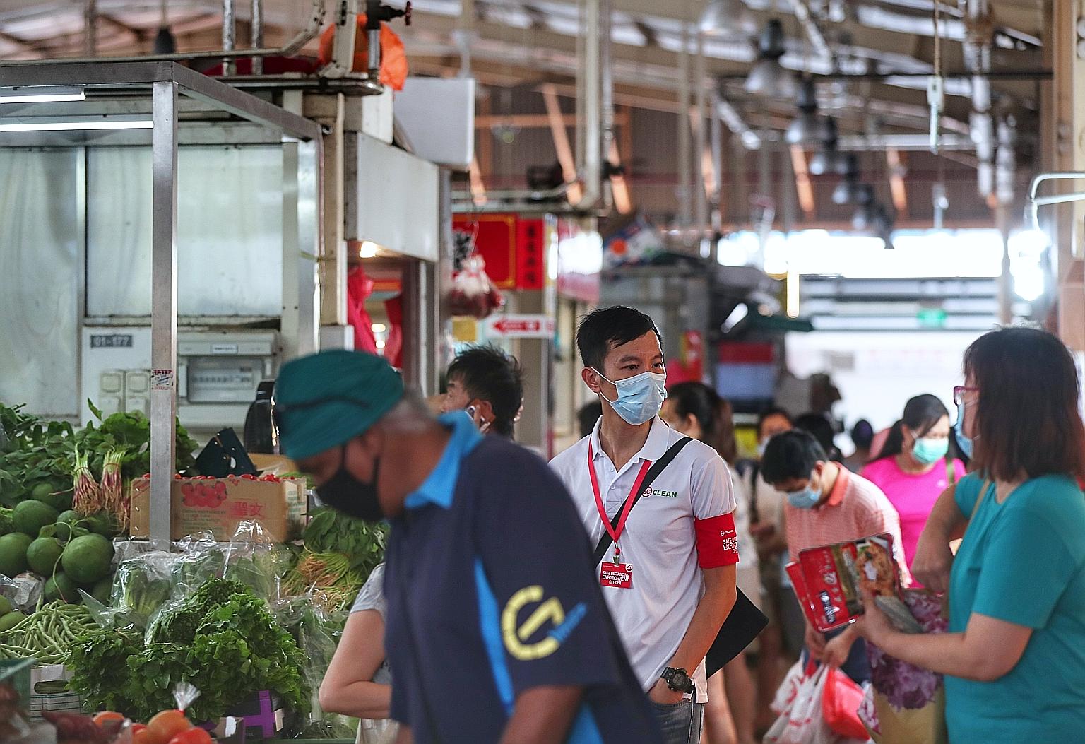 A safe distancing enforcement officer at work at a wet market. The Ministry of Sustainability and the Environment says agencies will continue to step up enforcement inspection of food and beverage premises, shopping malls, parks and beaches to curb a