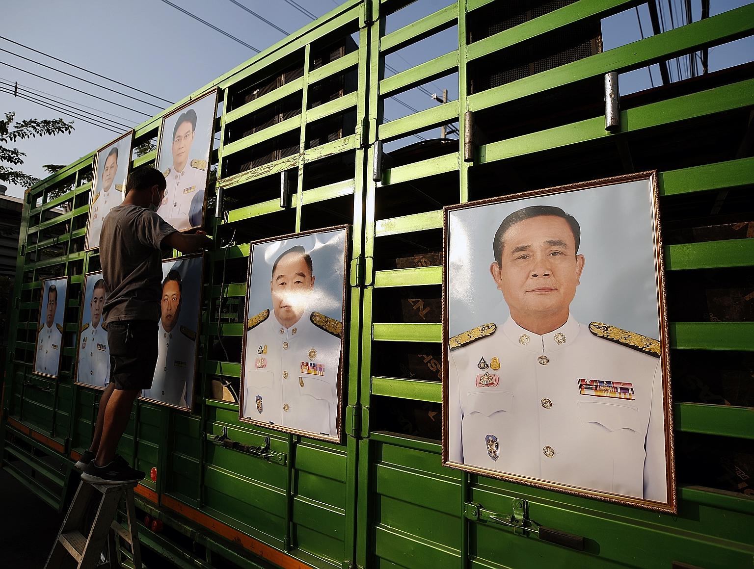 Photographs of Thai Prime Minister Prayut Chan-o-cha (far right) and members of his Cabinet being put up at an anti-government rally outside Parliament in Bangkok yesterday. The government's victory comes as pro-democracy protests returned after a lu