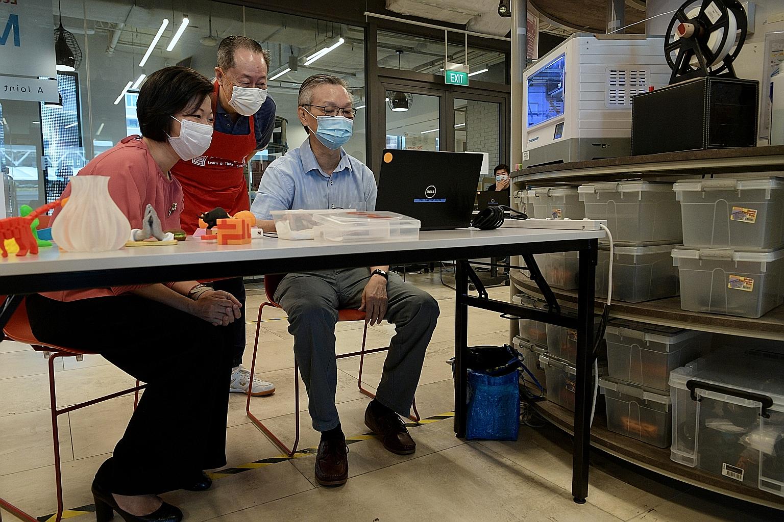 Senior Minister of State for Communications and Information Sim Ann at Tampines Regional Library watching Mr Chang Yoke Poon, 64, use the 3D printer. Also watching Mr Chang's progress is his teacher, Mr Andrew Koh, 66. ST PHOTO: NG SOR LUAN