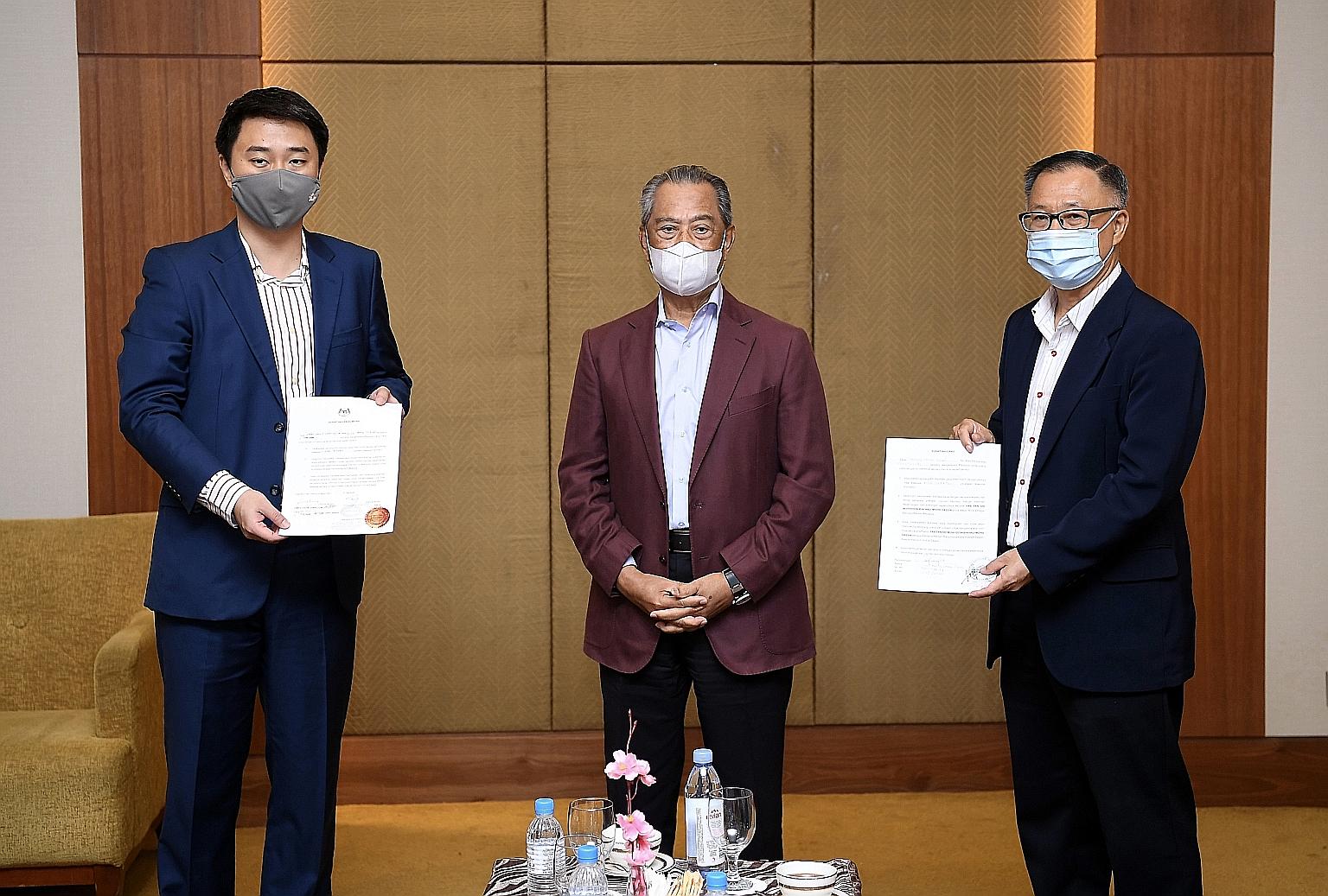Malaysian Prime Minister Muhyiddin Yassin flanked by opposition Parti Keadilan Rakyat MPs Larry Sng (left) and Steven Choong yesterday, when he received their statutory declarations of support for his Perikatan Nasional government, after a gathering 