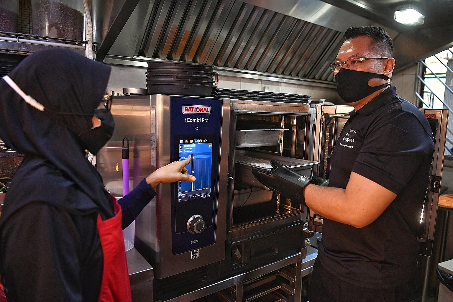 Mr Abdul Hadi Kamarolzaman, director of Istimewa Nasi Padang, using a combi oven at one of the company's two outlets yesterday. The oven enables staff to cook multiple dishes at the same time, without affecting the taste and aroma. ST PHOTO: CHONG JU