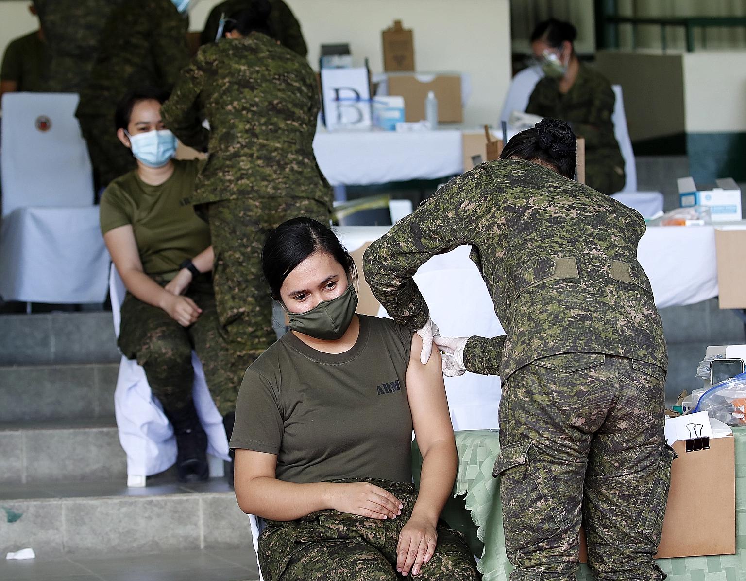 Military health workers giving Covid-19 shots yesterday to members of the armed forces in Taguig city, south of Manila. The Philippines began rolling out its Covid-19 immunisation programme on Monday, after it received about 600,000 doses of the vacc