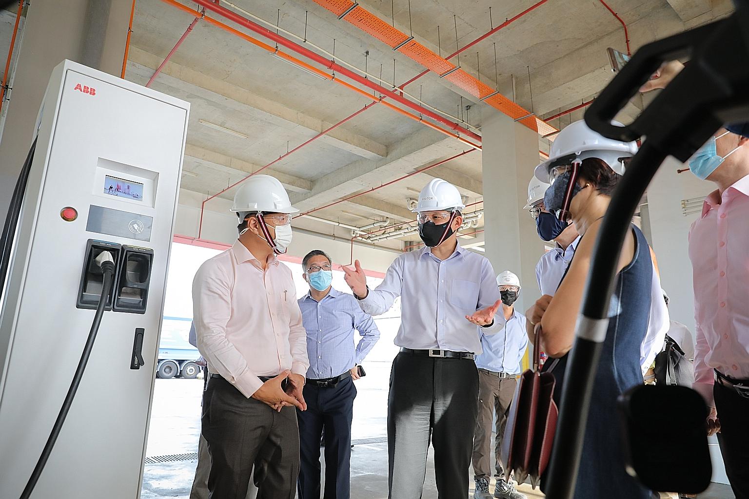 Trade and Industry Minister Chan Chun Sing (centre) checking out an electric charging station for refuse collection trucks, with (foreground, from left) 800 Super chief executive William Lee, the National Environment Agency's director of industry dev