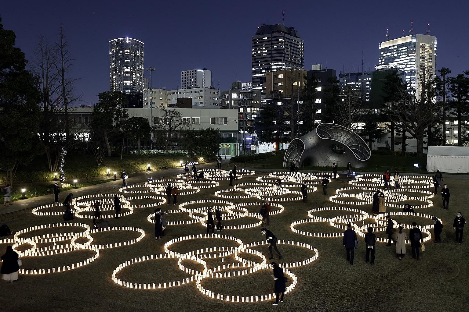 People in Tokyo looking at memorial lanterns, made from traditional Japanese paper, adorned with messages for victims of Japan's strongest earthquake in history, as the country marked the disaster's 10th anniversary yesterday. Some 22,000 people died