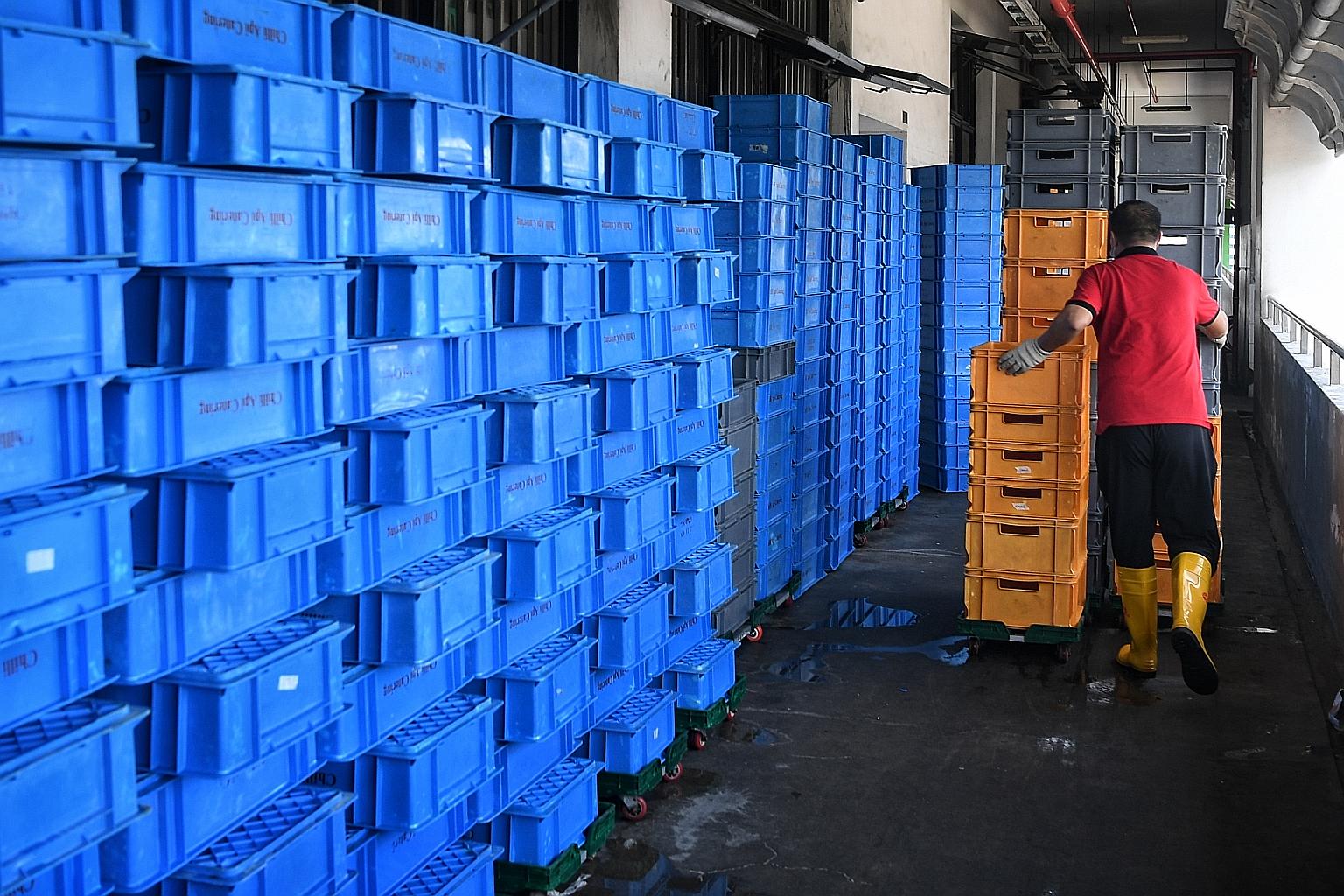 A worker leaving plastic containers out to dry after washing them outside Chilli Api Catering's kitchen in Bedok North Street 5 yesterday. The caterer was ordered to suspend operations from Sunday following a food poisoning outbreak. The affected TJC