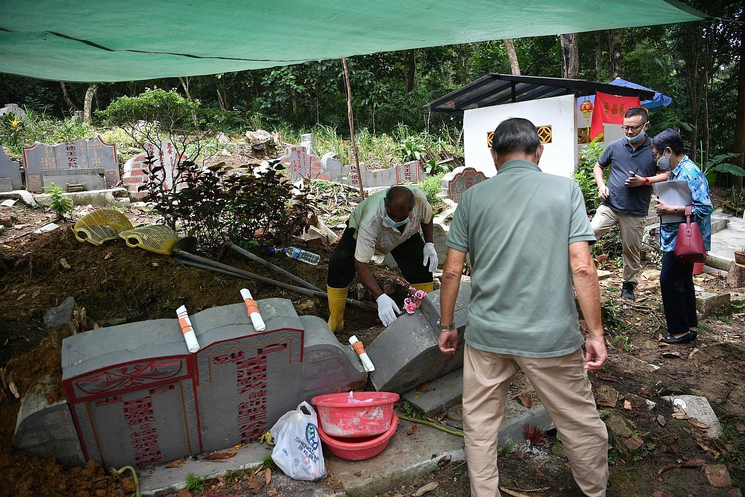 Descendants of Ong Chong Chew, a pioneer Chinese merchant, watching the exhumation of his grave in Bukit Brown Cemetery on Sunday. The location of the remains was found only four years ago by a "tomb hunter" employed by the family. The remains were c