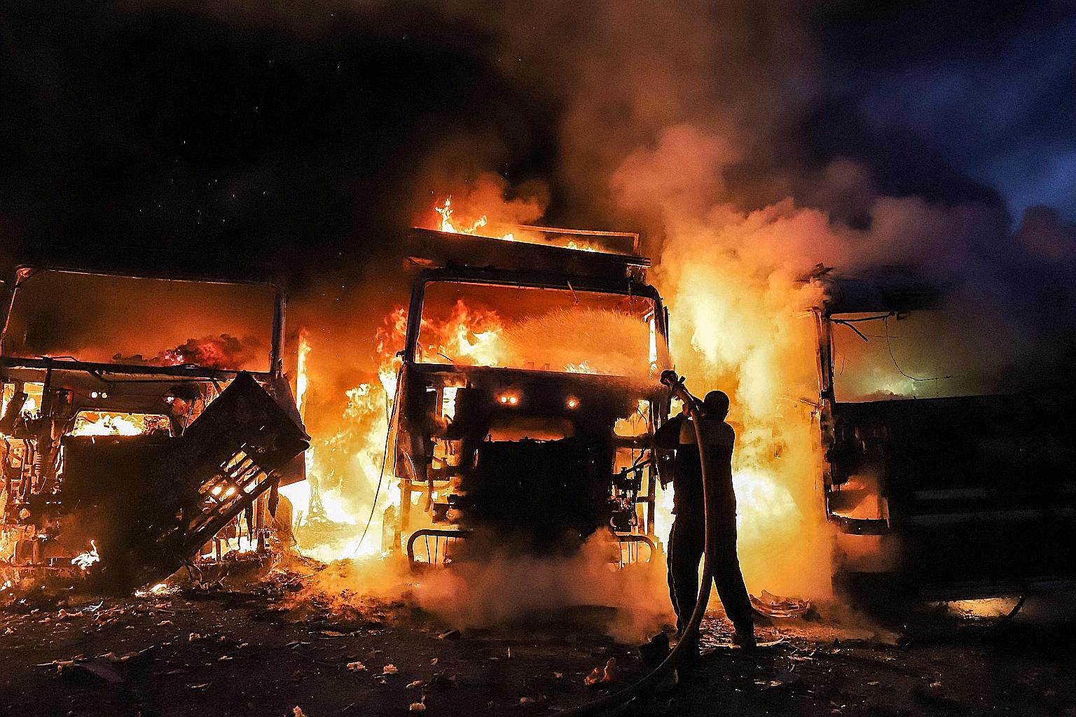 A Syrian civil defence member trying to put out a fire engulfing several vehicles following air strikes at a depot near the Bab al-Hawa border crossing between Syria and Turkey on Sunday. Russian air strikes came close to densely populated refugee ca