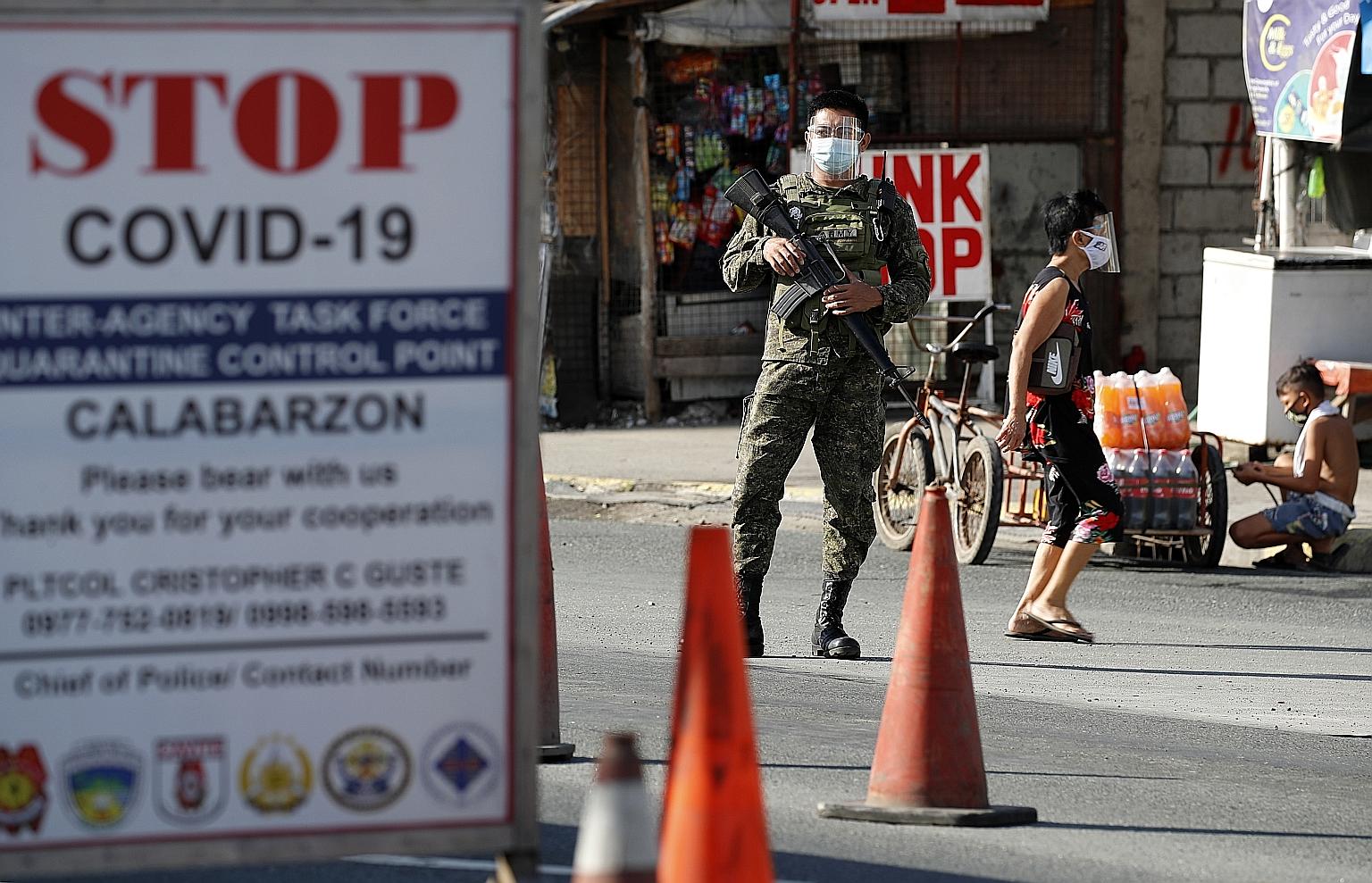 Security personnel manning a checkpoint at the border between Metro Manila and Cavite province in the Philippines yesterday. Leisure travel out of Metro Manila and four nearby provinces, including Cavite, has been banned in a bid to curb an outbreak 