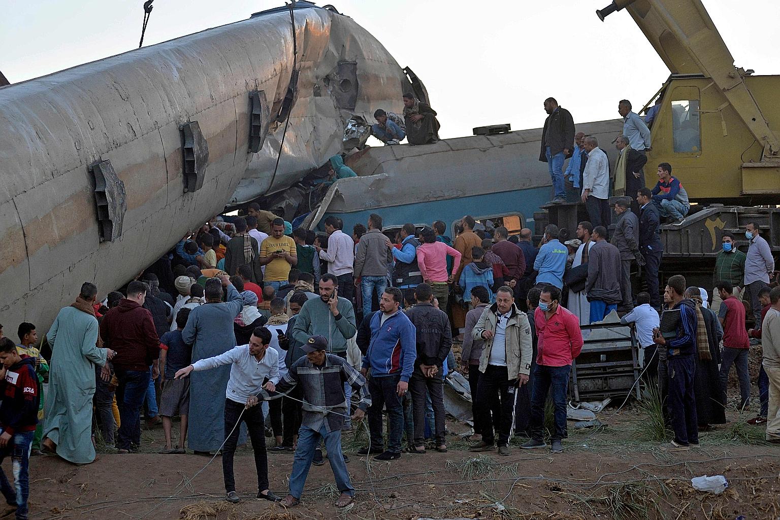 People gathering around the wreckage of two trains that collided on Friday in the Tahta district of Sohag province, 460km south of the Egyptian capital Cairo. PHOTO: AGENCE FRANCE-PRESSE