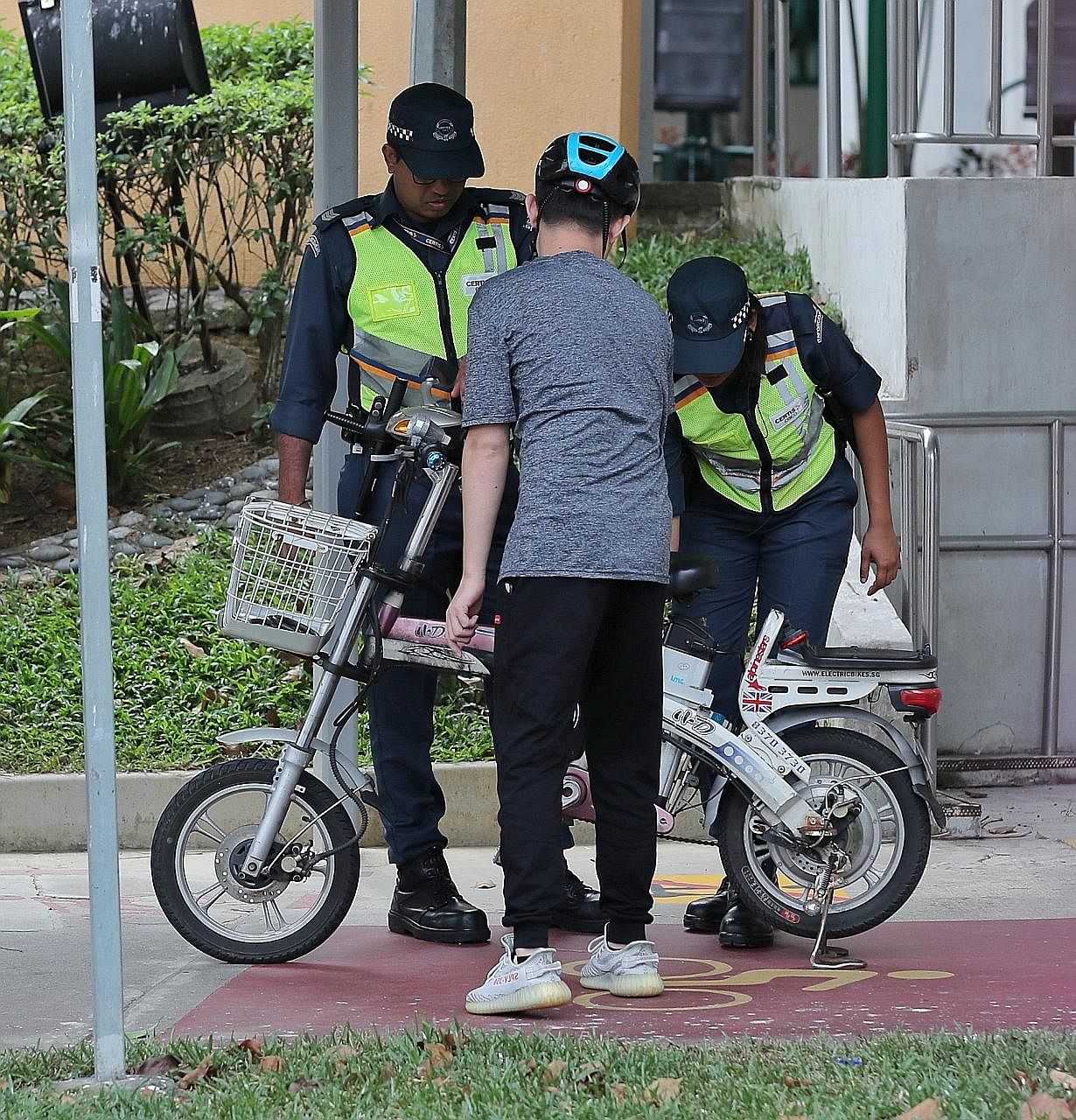 Auxiliary police officers advising an e-bike rider on where he can ride his device in Ang Mo Kio in January last year. Power-assisted bicycles are allowed on roads, cycling paths and shared paths, and are banned from footpaths. ST PHOTO: GAVIN FOO