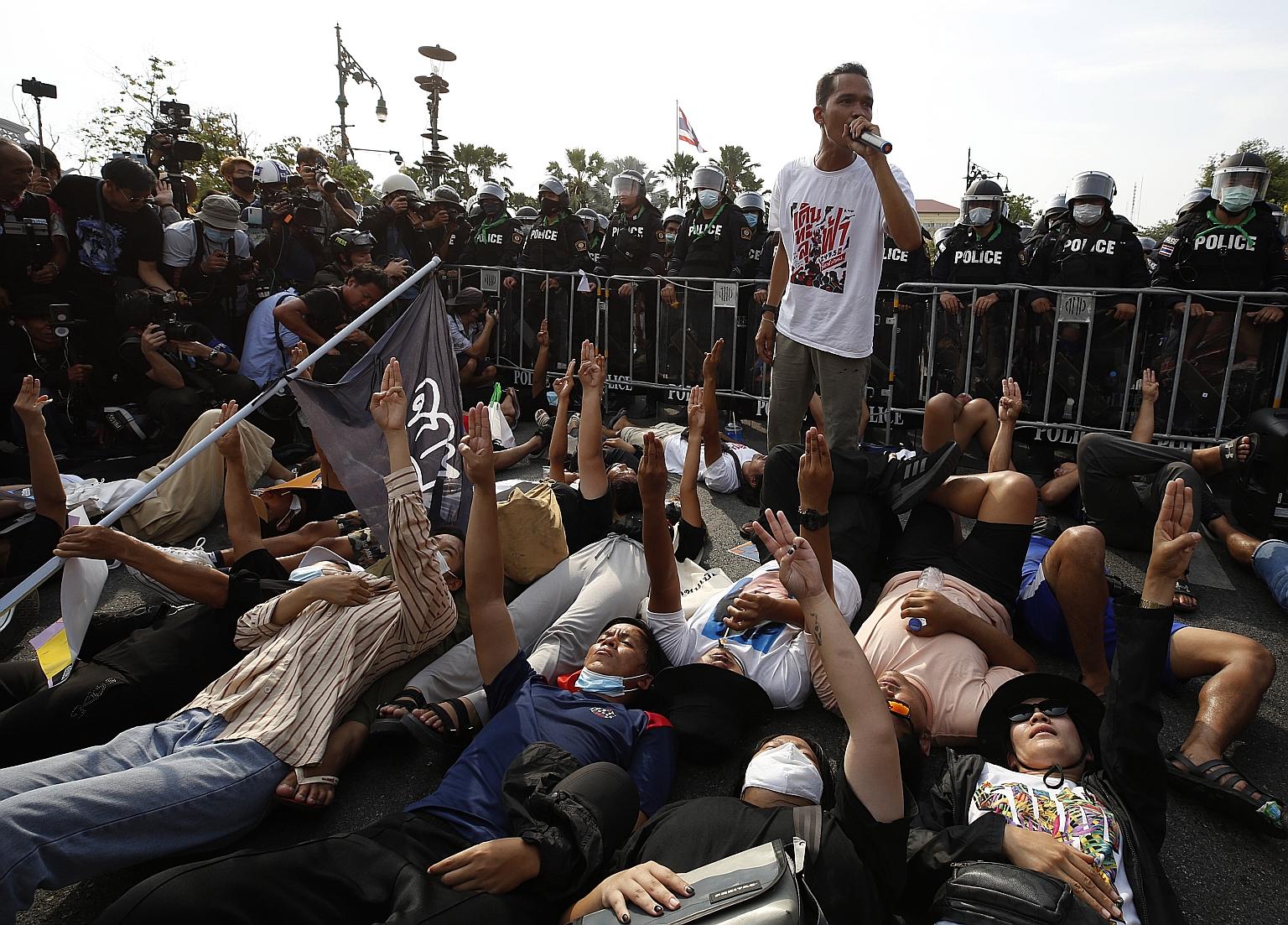 Anti-government protesters lying on the ground and flashing the three-finger salute in front of anti-riot police officers during a rally near the Government House in Bangkok on March 30. According to advocacy group Thai Lawyers for Human Rights, 581