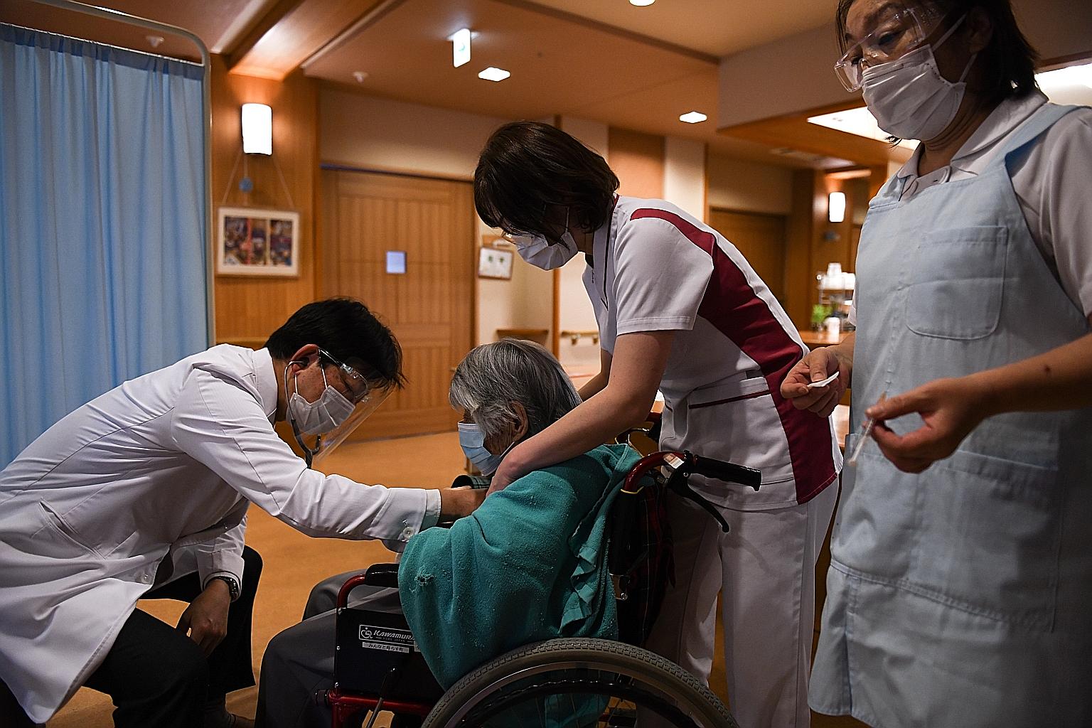 A doctor checking the heartbeat of a nursing home resident due to receive the Pfizer-BioNTech vaccine in Kawasaki, Kanagawa prefecture, yesterday. Japan has no domestically developed Covid-19 vaccine of its own, and its late roll-out stems from a dep