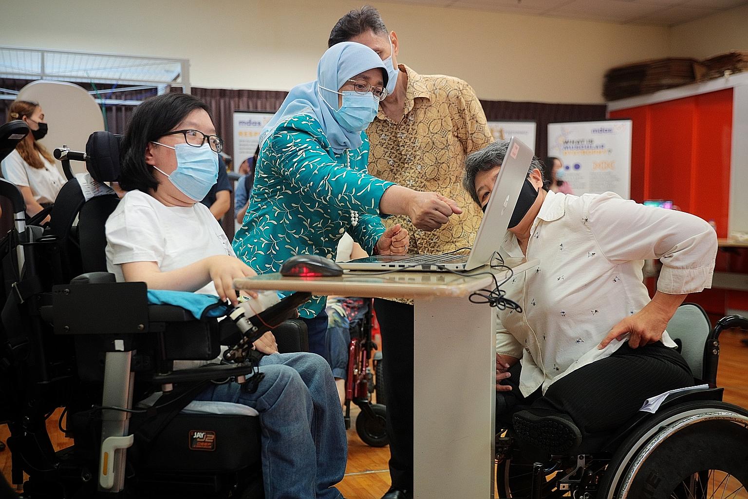 President Halimah Yacob viewing an animation created by Ms Jasmine Yau (far left), 27, a learner in the Bridge-Pro Framework, during a visit to the Muscular Dystrophy Association (Singapore) yesterday. With them were MDAS executive director Judy Wee