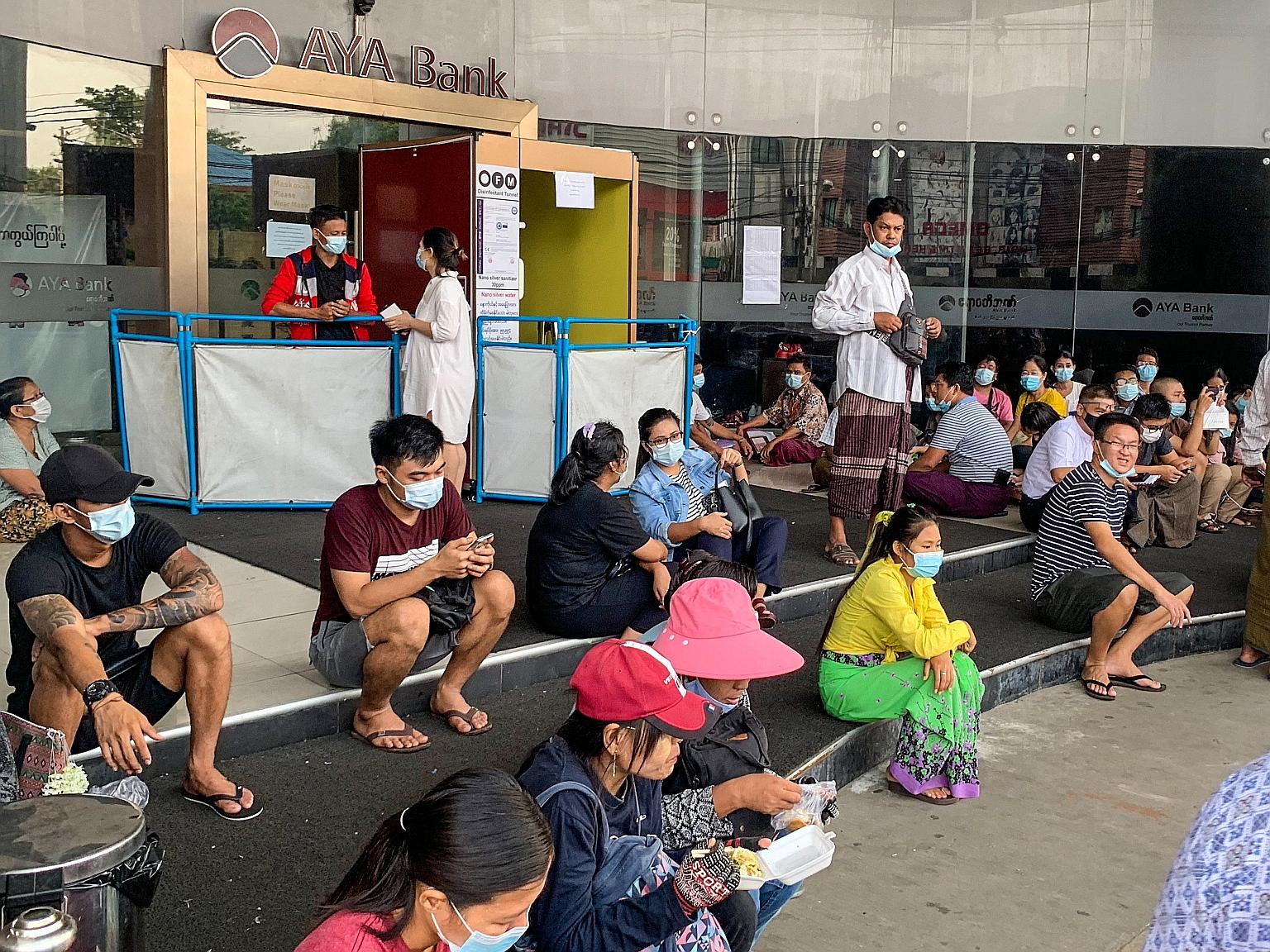 People waiting in Yangon yesterday for a branch of the AYA Bank to open, ahead of a long holiday stretch for the Myanmar New Year. Restrictions on cash withdrawals have led to businesses struggling to pay employees, among other signs of distress in t