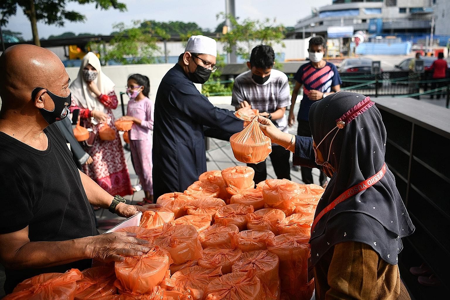 Staff and volunteers at Yusof Ishak Mosque in Woodlands distributing packets of porridge, a tradition during Ramadan - which began yesterday - to residents in the afternoon. A mosque spokesman said that 400 packets had been catered, of which 100 were