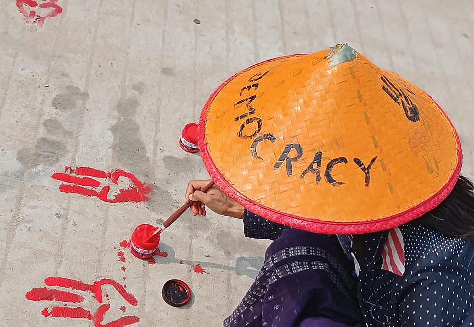 This photo, posted on Facebook and shared by an anonymous source yesterday, shows a protester painting the three-finger salute symbol on the ground with red paint as part of a "bloody paint strike" protest against the military coup in Shwebo, Myanmar
