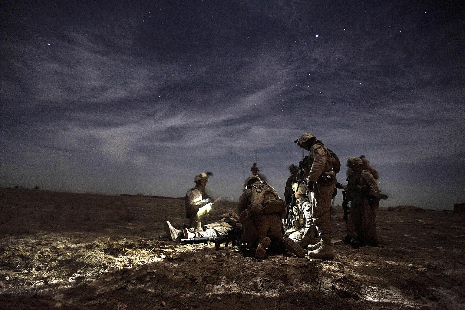 US Marines tending to a comrade injured by an improvised explosive device in Afghanistan in 2010. More than 2,400 Americans have died in the two-decade long war.